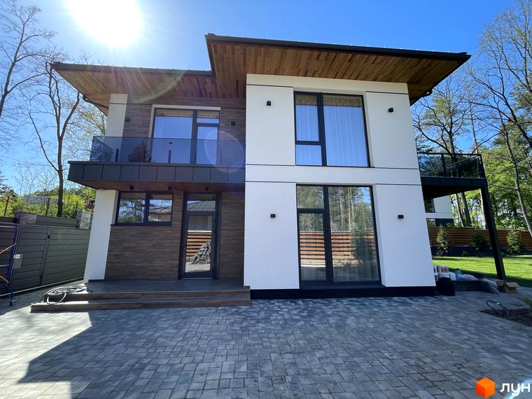 Котеджне містечко Нова Ходосівка Premium: двоповерховий будинок з дерев'яними елементами, скляними балконами та брукованою прибудинковою територією.