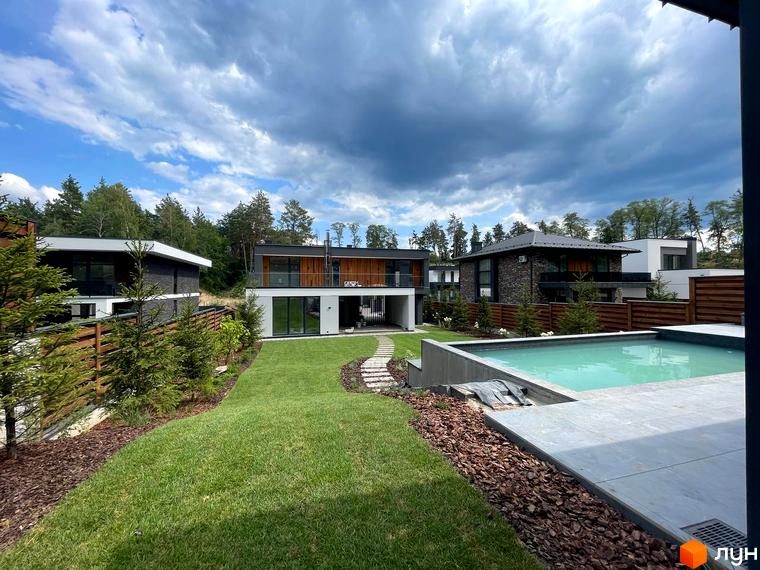 Котеджне містечко Нова Ходосівка Premium з басейном та доглянутим газоном. Сучасні будинки з дерев'яними та кам'яними фасадами на тлі хмарного неба.