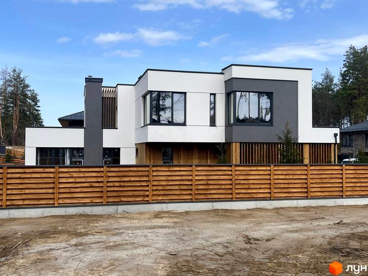Котеджне містечко КМ Нова Ходосівка Premium. Будинок з білою та сірою обробкою фасаду, великими вікнами та дерев'яним парканом.
