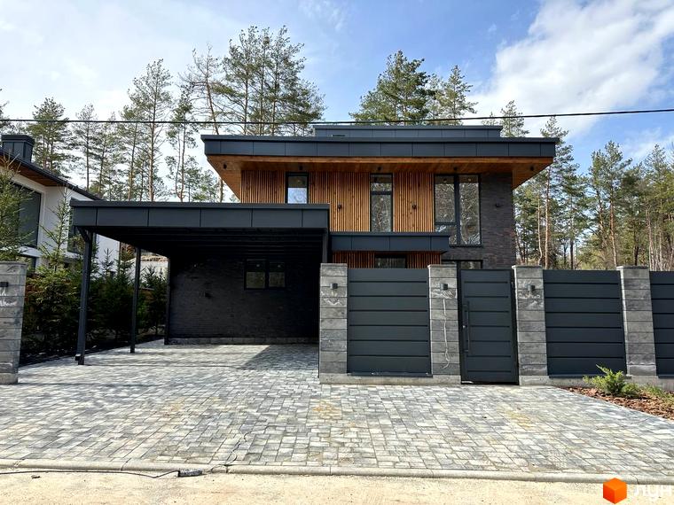 Котеджне містечко КМ Нова Ходосівка Premium. Фасад будинку з дерев'яними елементами та цегляною кладкою, прибудинкова територія з бруківкою та парканом.