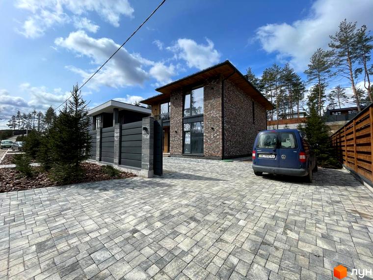 Котеджне містечко КМ Нова Ходосівка Premium: цегляний будинок з великими вікнами та синій мінівен на бруківці біля будинку.