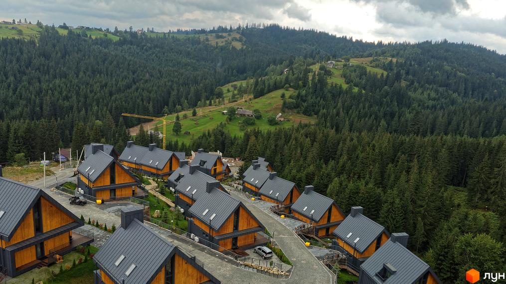 Вид зверху на Котеджне містечко SKOGUR з будинками з дерев'яним фасадом та сірими дахами. Навколо зелені гори та ліс.