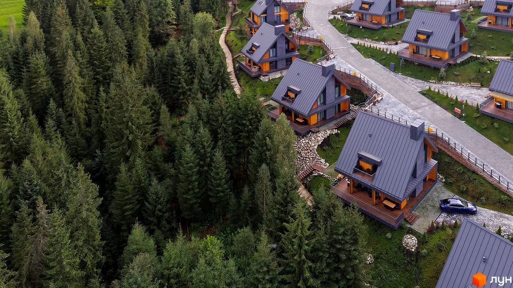 Вид зверху на Котеджне містечко SKOGUR з будинками з сірими дахами та дерев'яним оздобленням, навколо хвойний ліс.