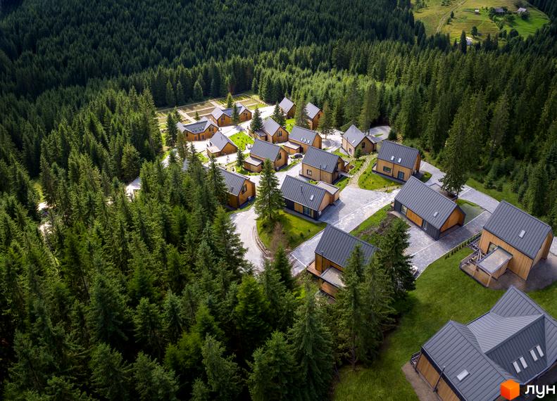 Вигляд з висоти на Котеджне містечко SKOGUR серед соснового лісу. Будинки з сірими дахами та дерев'яним оздобленням, доглянута територія.