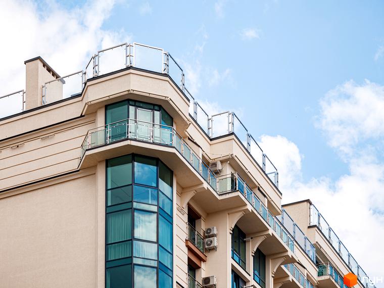 Фасад житлового комплексу HydroPark DeLuxe світлого кольору з великими вікнами та балконами зі скляними огорожами. Видно верхні поверхи будівлі.