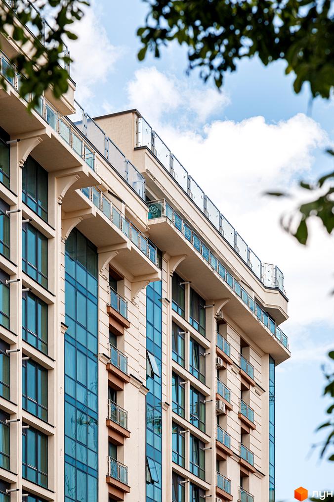 Житловий комплекс HydroPark DeLuxe: багатоповерховий будинок з бежевим фасадом, великими синіми вікнами та скляними балконами.