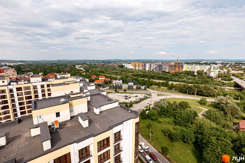 Вид на новобудову ЖК Lystopad з фасадами світло-жовтого та білого кольорів. Територія комплексу оточена зеленню та міською забудовою.