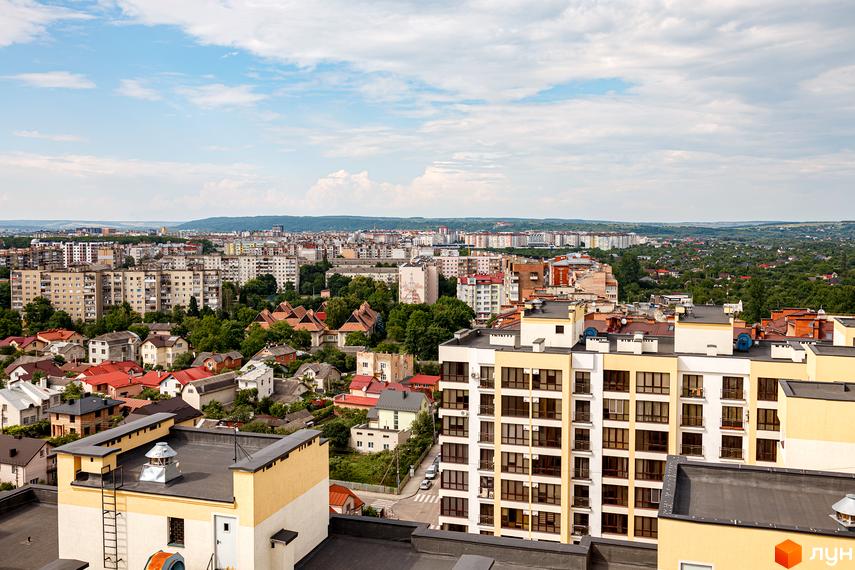 Вид на житловий комплекс Lystopad з висоти пташиного польоту. Багатоповерхові будинки з балконами та вікнами, оточені зеленню та іншими будівлями.