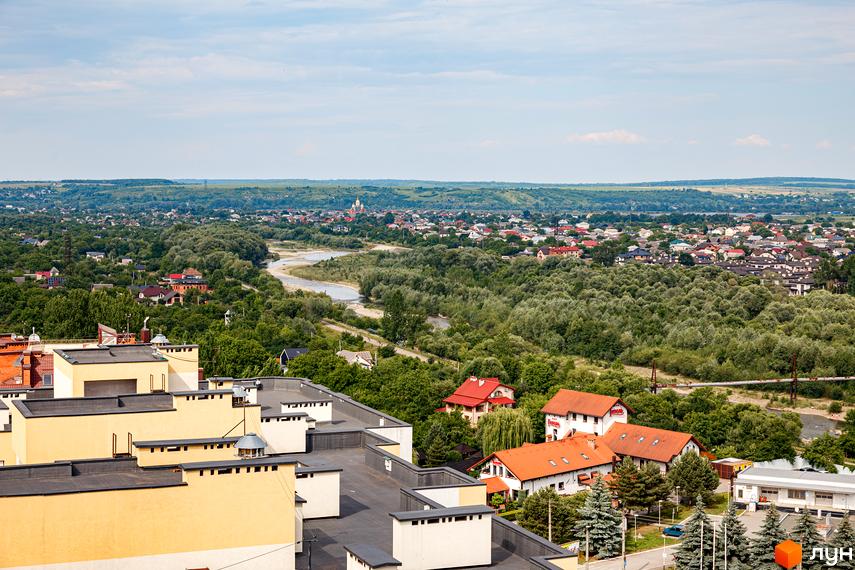 Вид на житловий комплекс Lystopad з висоти пташиного польоту, що демонструє сучасні будівлі та зелену прибудинкову територію. Навколо комплексу розташовані дерева та річка.