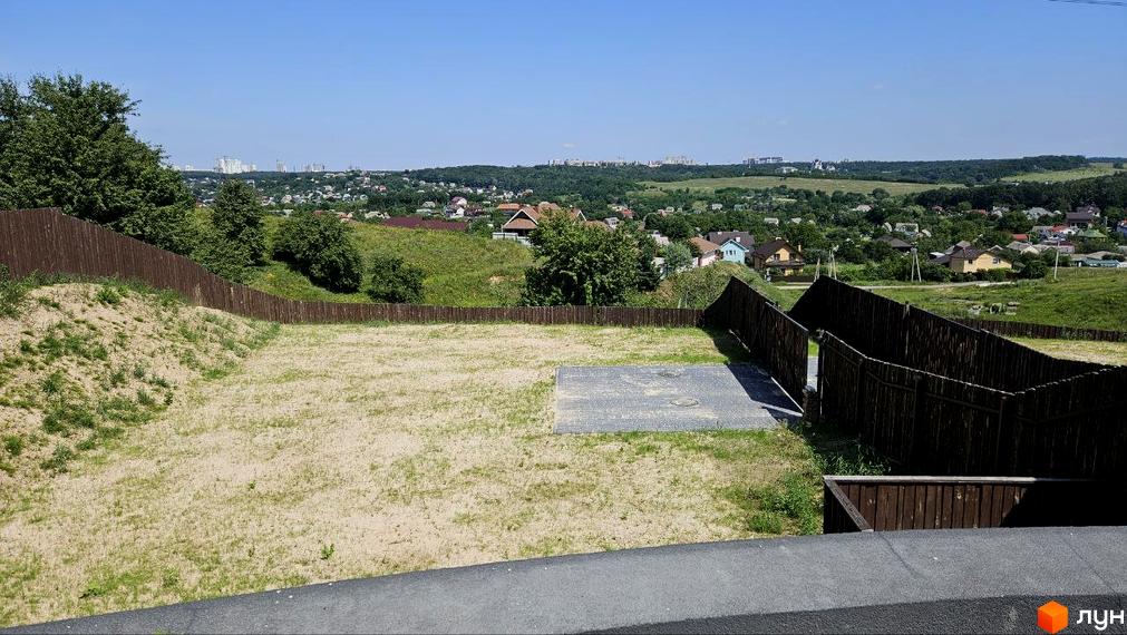 Котеджне містечко KRAIEVYD: вид на зелені пагорби та приватні будинки з дерев'яним парканом навколо ділянки.