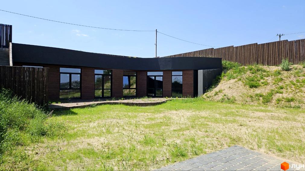 Котеджне містечко KRAIEVYD: будинок з коричневою обшивкою та великими вікнами, прибудинкова територія з травою та піском.