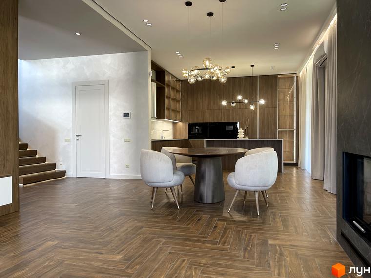 Інтер'єр кухні-вітальні в Котеджному містечку Нова Ходосівка. Обідній стіл та стільці на фоні кухонних меблів.