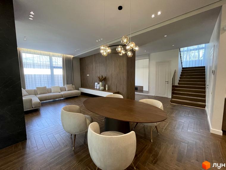 Інтер'єр Котеджного містечка Нова Ходосівка: вітальня з великим столом та диваном біля вікна. Сходи на другий поверх.