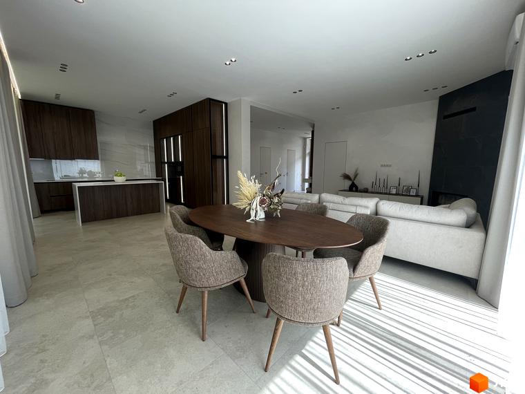 Інтер'єр вітальні в Котеджному містечку Нова Ходосівка з обіднім столом та диваном. Просторе приміщення з великими вікнами та сучасним дизайном.