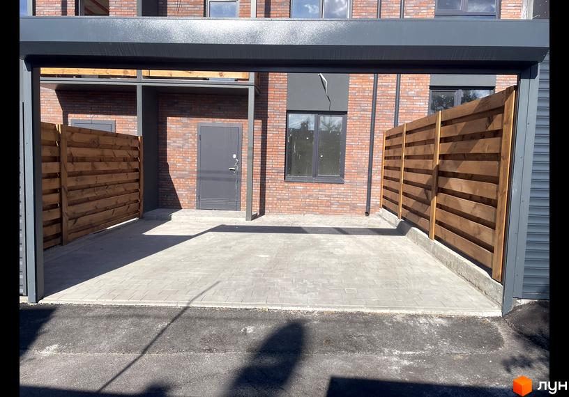 Таунхауси Сингаївського: зовнішній вигляд цегляної новобудови з дерев'яними парканами та вимощеною територією.