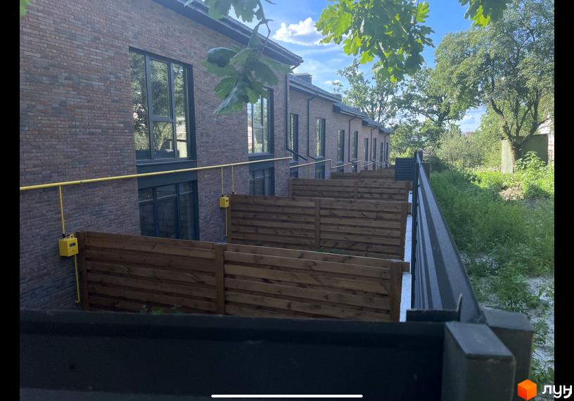 Таунхауси „Сингаївського“: цегляні фасади, дерев'яні паркани та зелена територія. Ознайомтеся з проєктом на сайті.