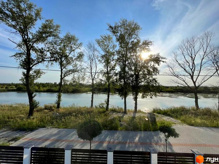 КМ Sunrise Residence: мальовничий краєвид на річку з деревами та зеленню на березі. Територія комплексу з доглянутими доріжками та парканом.