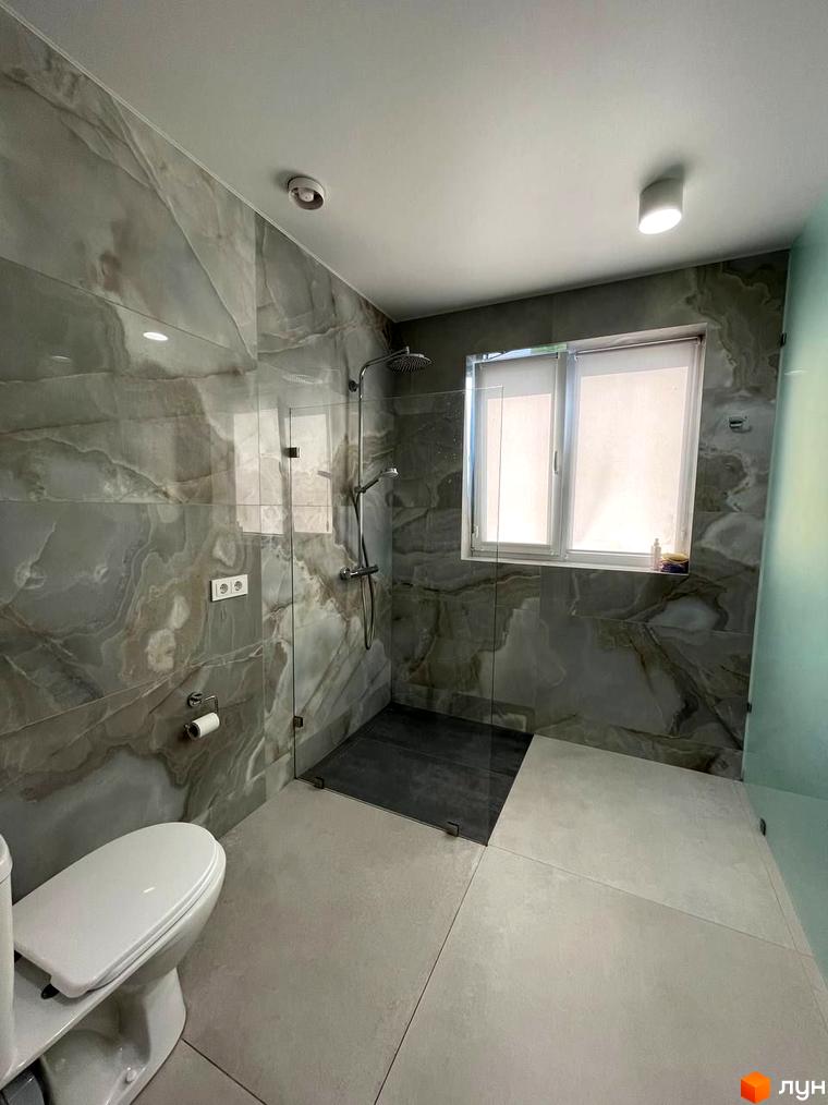 Дизайн ванної кімнати в новобудові КМ Sunrise Residence з мармуровим оздобленням стін, душовою кабіною та туалетом.