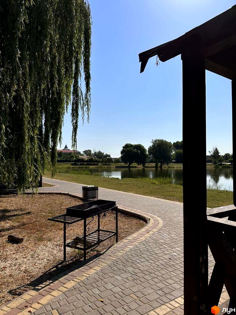 Житловий комплекс Riviera: зелена зона біля водойми з альтанкою та мангалом. Відкритий простір для відпочинку та барбекю.