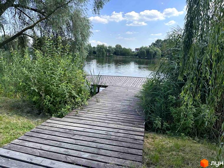 Причал біля озера в ЖК Riviera з деревами та зеленою територією. Відпочинок на природі біля води.