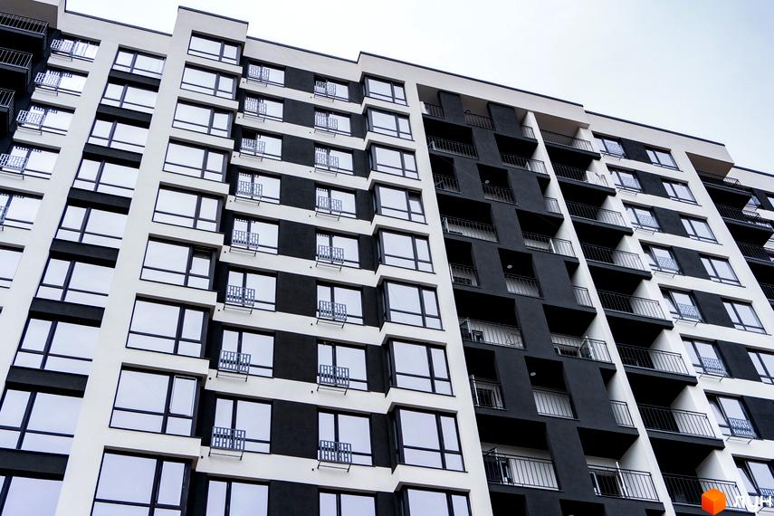 Фасад житлового комплексу А5, чорно-біла новобудова з великою кількістю вікон та балконів. Зовнішній вигляд будинку з низькою прибудинковою територією.