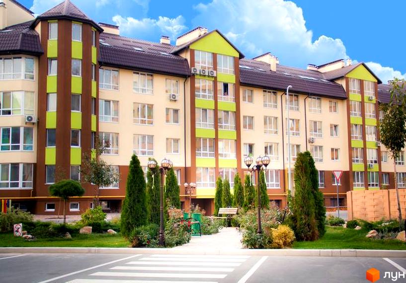 Житловий комплекс Львівський маєток. Фасад будинку в бежевих та коричневих тонах з зеленими вставками. Озеленена прибудинкова територія з деревами та ліхтарями.