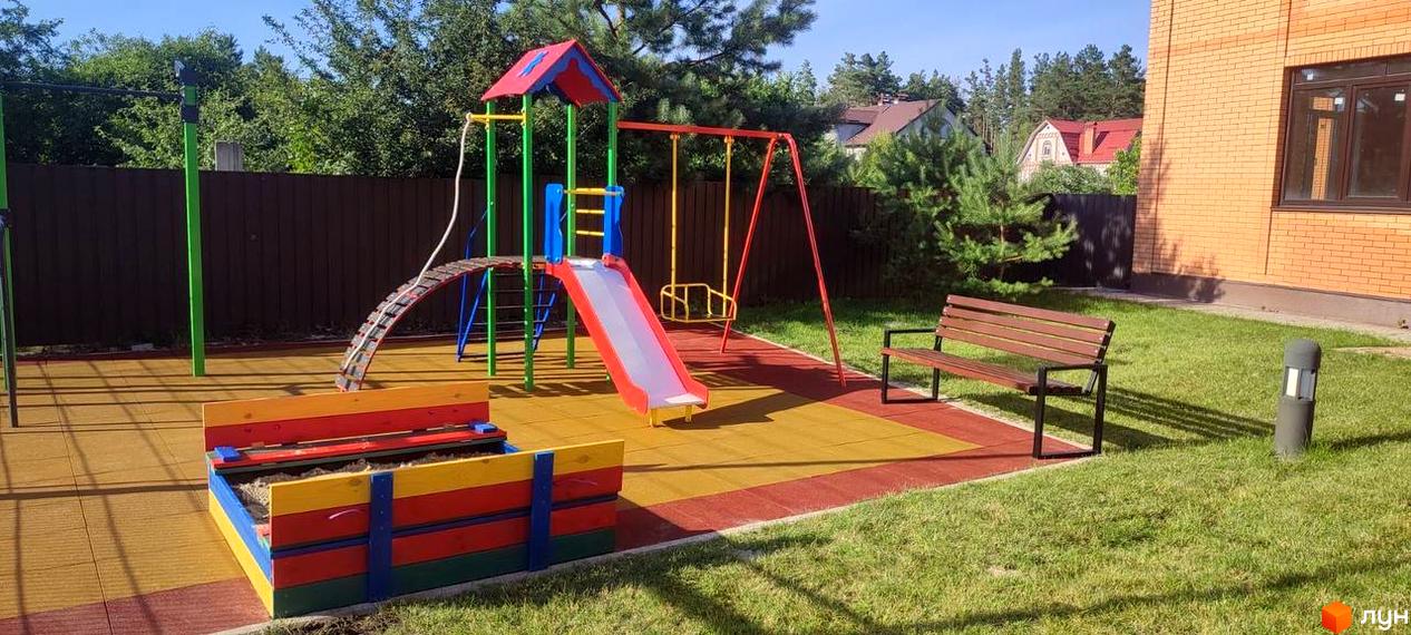 Дитячий майданчик біля цегляної новобудови ЖК Мюнхен. На території є гірка, гойдалка, пісочниця та лавка.