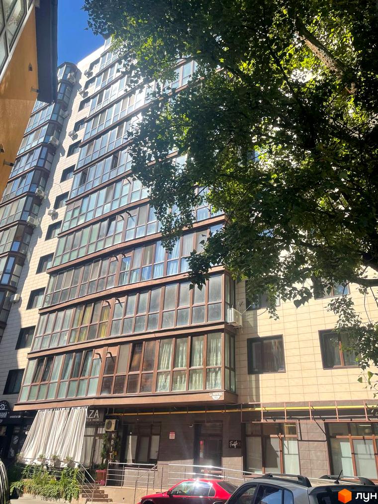 Житловий комплекс Pirogovsky – це багатоповерхова будівля зі скляними фасадами та балконами, що виходить на вулицю з деревами та комерційними приміщеннями на першому поверсі.