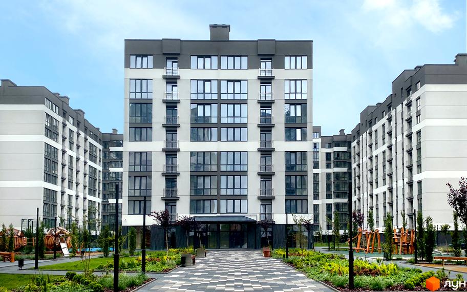 Фасад багатоповерхового будинку ЖК Козацький з великими вікнами та балконами. На території комплексу доглянуті газони та доріжки.