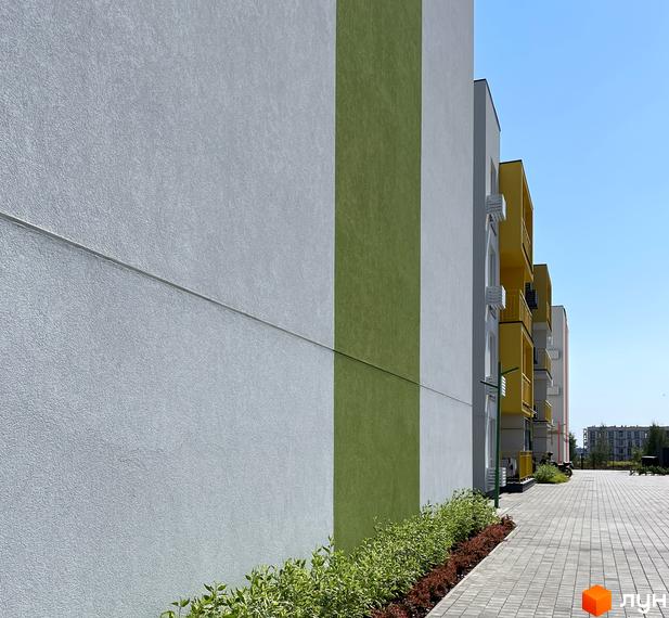 Фасад житлового комплексу Art Misto з білими та зеленими смугами, жовтими балконами та вимощеною плиткою прибудинковою територією.