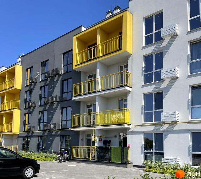 Новобудова ЖК Art Misto з яскравими жовтими балконами та сірими фасадами. Біля будинку розташована прибудинкова територія з парковкою та зеленими насадженнями.