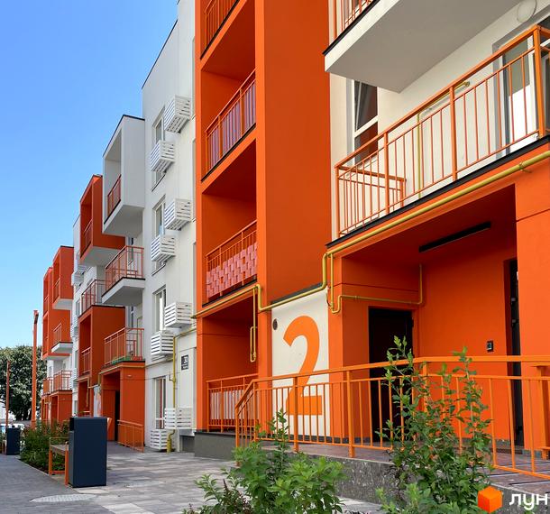 Житловий комплекс Art Misto з яскравим фасадом та балконами, розташований біля доглянутої прибудинкової території з зеленню.