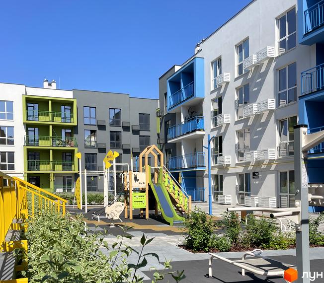 Житловий комплекс Art Misto: фасади будинків з яскравими елементами та дитячий майданчик з гірками та гойдалками.