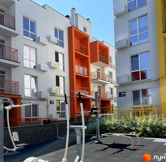 Житловий комплекс Art Misto: фасади будівель з яскравими помаранчевими елементами та балконами, прибудинкова територія з тренажерами.