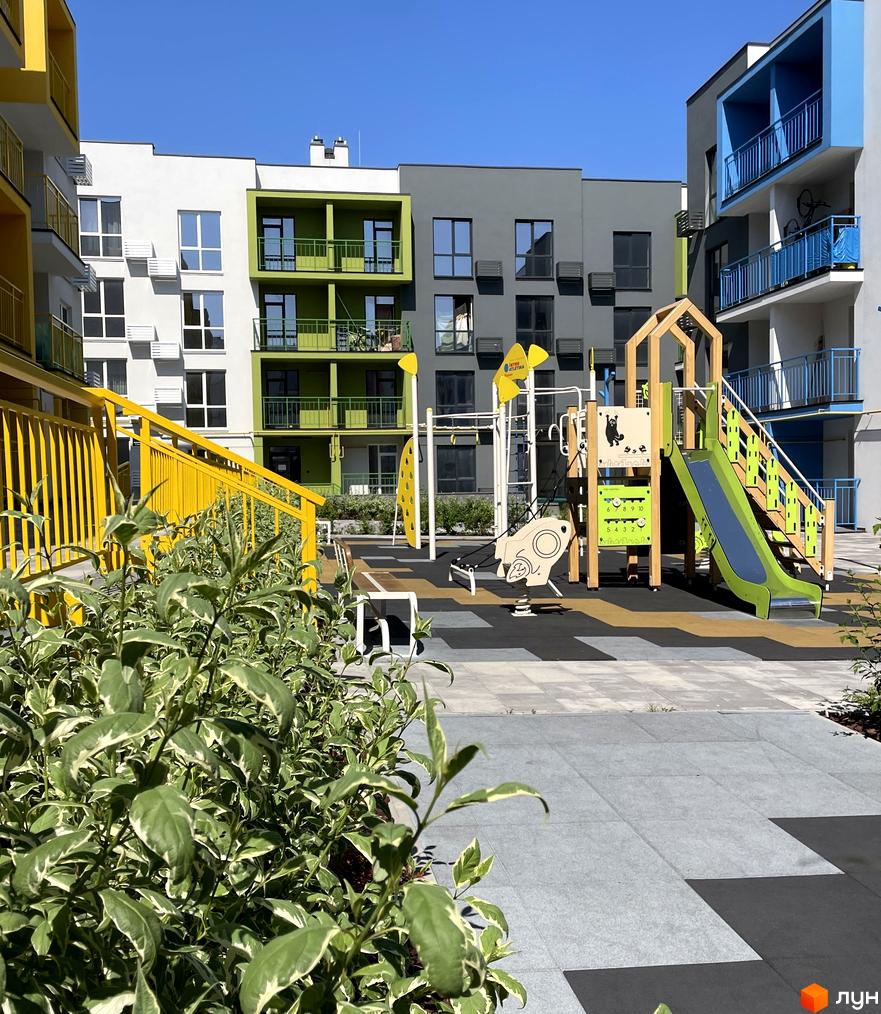 Новобудова ЖК Art Misto з яскравим фасадом та дитячим майданчиком у дворі. Зелені та жовті елементи будівель створюють затишну атмосферу.
