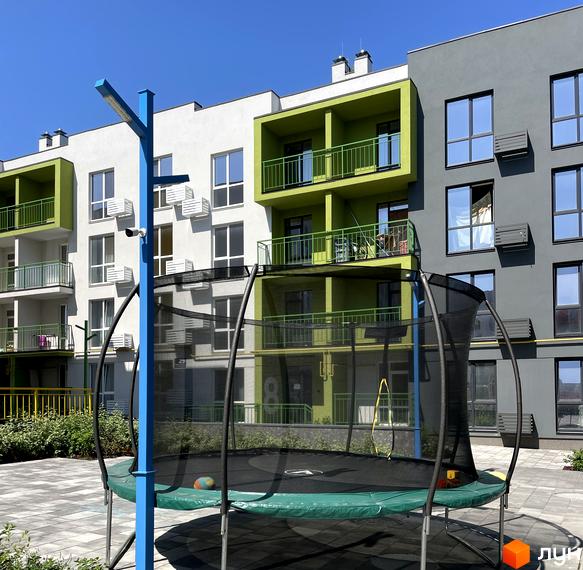 Житловий комплекс Art Misto з яскравими зеленими балконами та сірими фасадами, дитячим майданчиком з батутом на прибудинковій території.