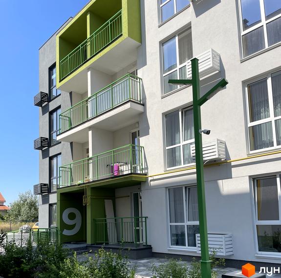 Житловий комплекс Art Misto з сірим фасадом та зеленими елементами, балконами та вікнами. Навколо будинку зелені насадження та доглянута територія.