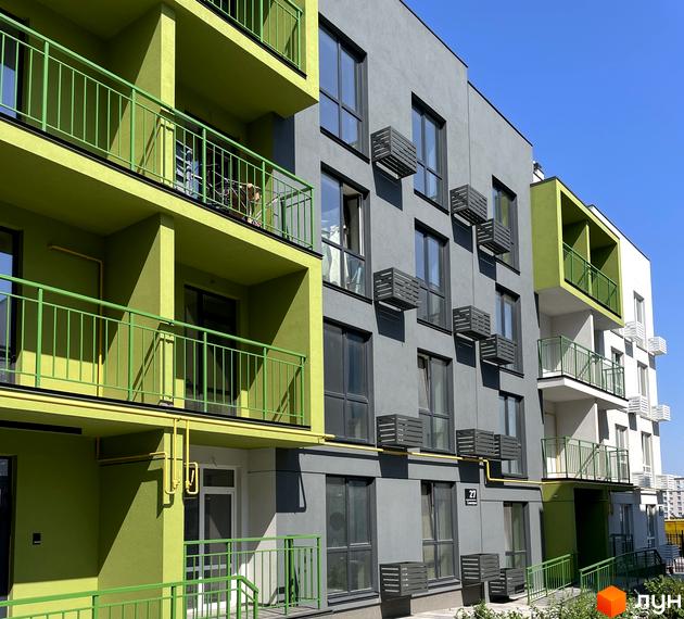 Житловий комплекс Art Misto з яскравими зеленими балконами та сірими фасадами на тлі блакитного неба. Навколо новобудови видно кондиціонери та вікна.