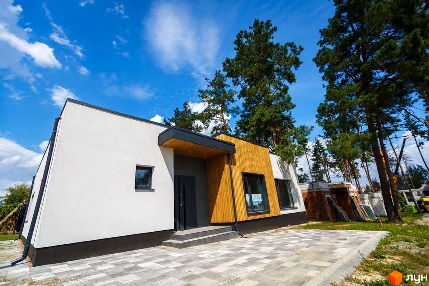 Сучасний житловий комплекс VISION з білою фасадною штукатуркою та дерев'яними елементами. Навколо будинку облаштована прибудинкова територія з бруківкою та зеленими насадженнями.