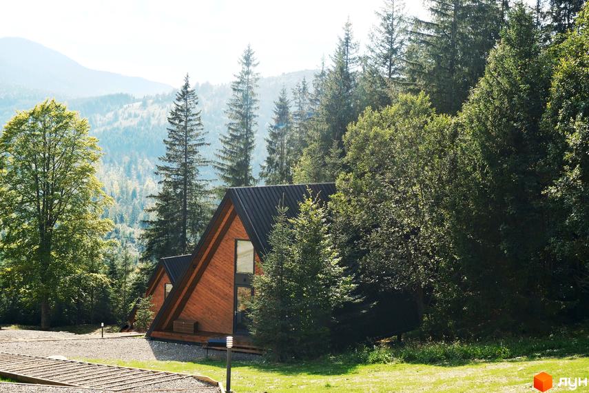 Комплекс відпочинку УЛІС – дерев'яні будинки у Карпатах. Навколо комплексу зелені дерева та гори.