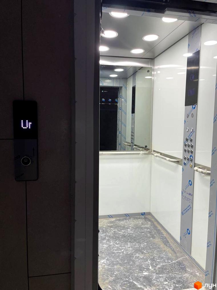 Сучасний ліфт у житловому комплексі ЖК AcademHoff з панеллю керування та відображенням поверху. Інтер'єр ліфта виконаний у білих тонах з дзеркальними елементами.