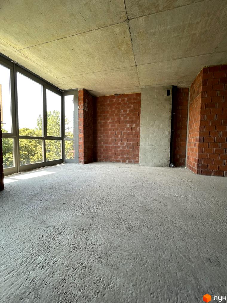 Будівельний проєкт ЖК AcademHoff. Незавершений ремонт у кімнаті з великими вікнами та цегляними стінами.