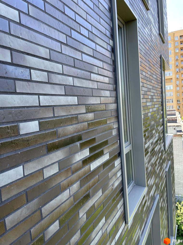 Фасад житлового комплексу ЖК AcademHoff з цегляним оздобленням та вікнами. Зовнішній вигляд новобудови.