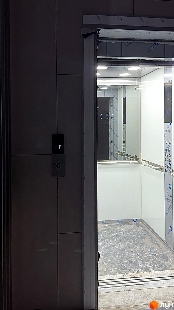 Зовнішній вигляд будинку ЖК AcademHoff. Всередині ліфта видно панелі з кнопками виклику та дзеркалами.