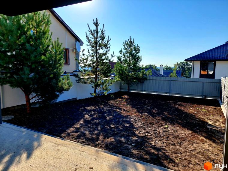 Дуплекси Woodland Hill: світлі будинки з темними дахами та простора прибудинкова ділянка з молодими соснами.