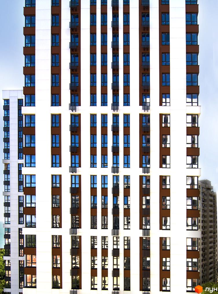 Фасад житлового комплексу Sea View з коричневими та білими елементами та численними вікнами. Вид на багатоквартирний будинок з блакитними вікнами та балконами.