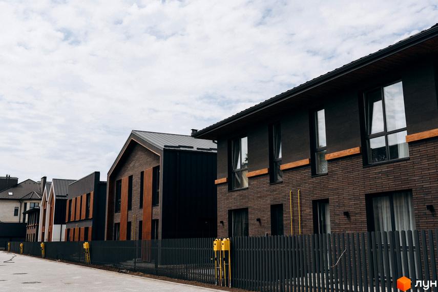 Котеджне містечко КМ Garden Village Ozerne. Зовнішній вигляд будинків з коричневої цегли та темних панелей, огороджена територія.