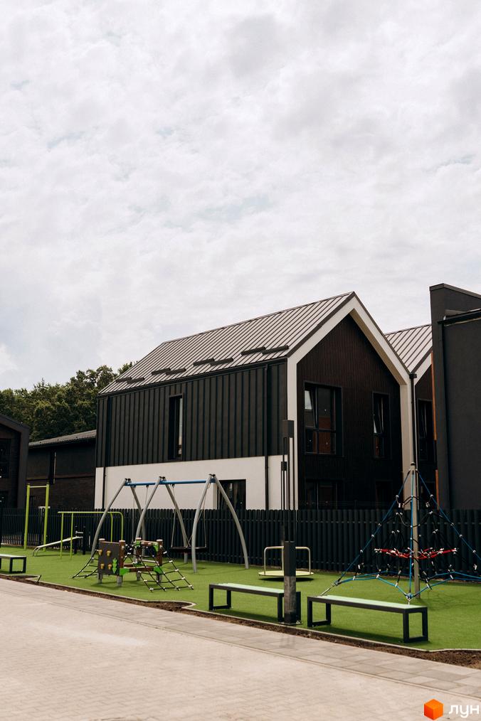 Котеджне містечко КМ Garden Village Ozerne: сучасні будинки з темним фасадом та дитячим майданчиком з гойдалками та гіркою.