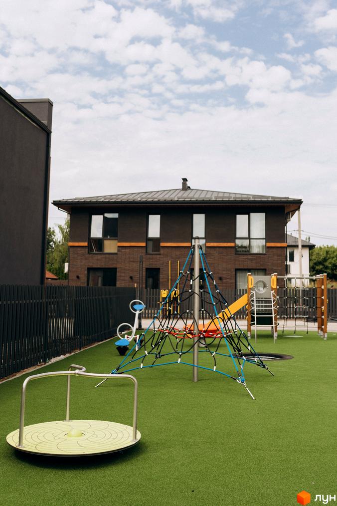 Котеджне містечко КМ Garden Village Ozerne з цегляним фасадом та дитячим майданчиком на зеленій території. Фото новобудови.