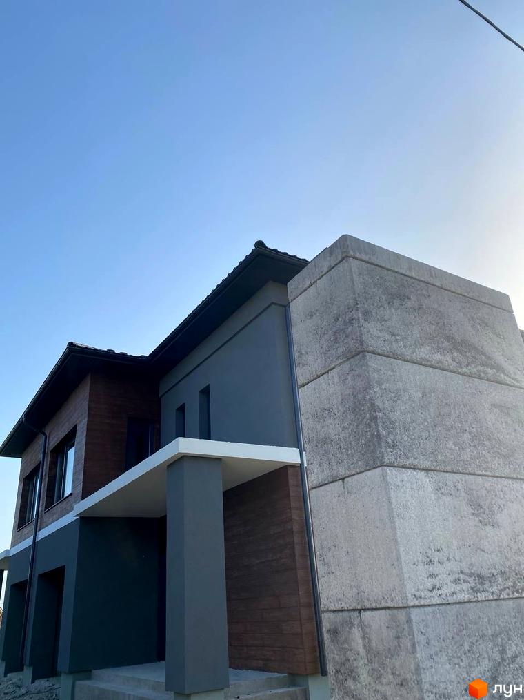 Сучасний житловий комплекс на вулиці Волошкова з фасадом з дерев'яних панелей та сірої штукатурки. Будинок має великі вікна та бетонні елементи.